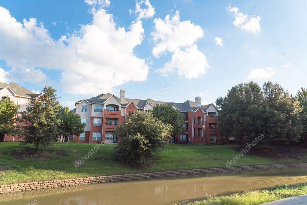 Typical multistory riverside apartment building complex surrounded by mature trees in Irving, Texas, USA.