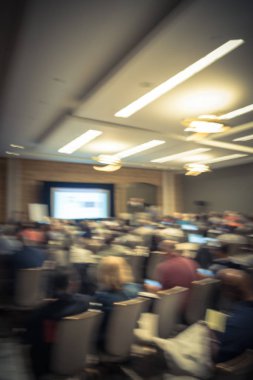Vintage sesi iş Seminer Toplantı ile Led projektör perde, sahne alanı'nda konuşmacı konuşma bulanık. Konferans Salonu Oda, dinleme talk-show dikiz seyirci defocused. Eğitim, iş kavramı