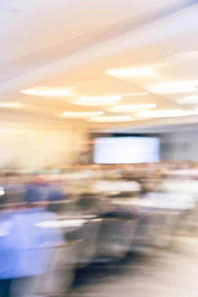 Blurred business seminar meeting with LED projector screen and speaker speech on stage. Defocused rear view audience in conference hall room, listening talk show in USA. Education, business concept