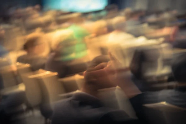 Blurred business seminar meeting with LED projector screen and speaker speech on stage. Defocused rear view audience in conference hall room, listening talk show in USA. Education, business concept