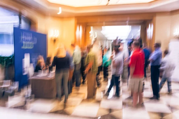 Abstract blurred participants queue line and check-in at registration table of business workshop in America. Multiethnic people sign-up and received instruction, event package from support staff