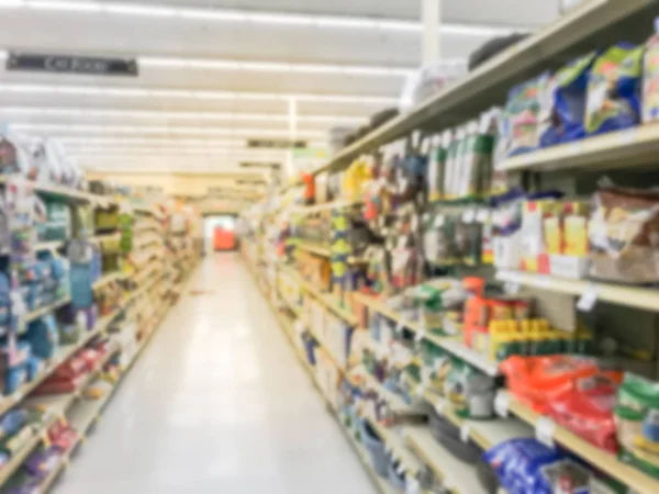 Abstract blurred dog and cat food shelves at American supermarket. Defocused pet supplies, laundry, dish soap, cat litter, pet and home care aisle row display with price tags.