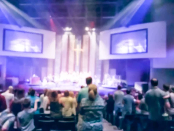 Motion blurred silhouettes of crowd people assembled for religious worship in front of bright stage lights. Eucharist therapy bless god helping repent catholic Easter lent mind pray.