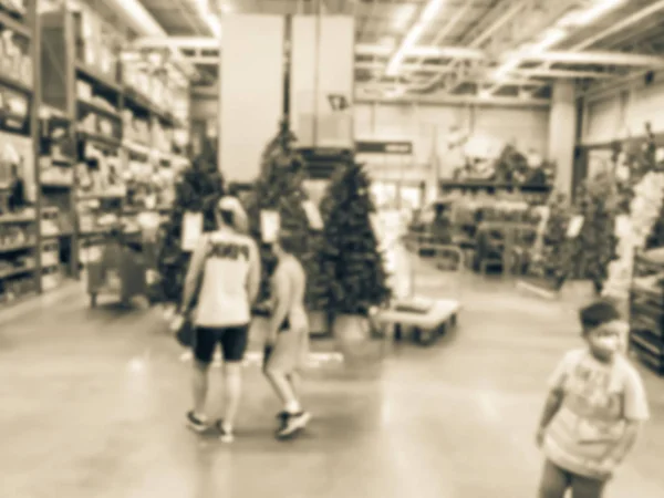 Vintage tone blurred customer shopping with flatbed cart for artificial Christmas tree multi-color lights at hardware store. Classic, decorated Xmas color changing wreaths, strings bokeh ornaments