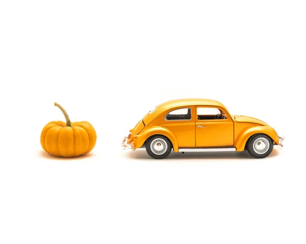 Studio shot orange toy car and mini pumpkin isolated on white background, small metal model car. Halloween fun concept
