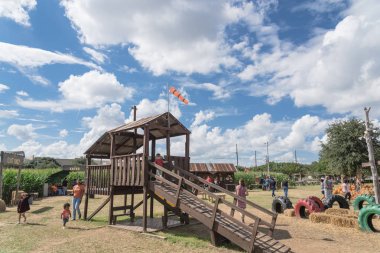 GRAPEVINE, TX, USA-OCT 6, 2018:Countryside old wooden playground with kids playing at pumpkin farm in rural of Grapevine, Texas, USA clipart
