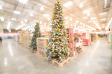 Bulanık renkli uzun yapay ağaç süsleme ve Noel malzemeleri toptan Store'da Teksas, ABD içinde. Çelenk ve dizeleri Xmas ağacı çevreleyen bokeh ışıkların. Tatil arka plan