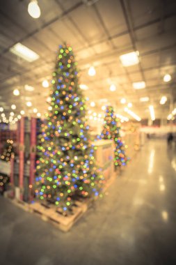 Bulanık renkli uzun yapay ağaç süsleme ve Noel malzemeleri toptan Store'da Teksas, ABD içinde. Çelenk ve dizeleri Xmas ağacı çevreleyen bokeh ışıkların. Tatil arka plan