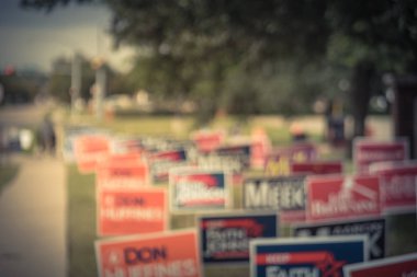 Vintage tone blurred row of yard signs at residential street for primary election day in Dallas county, Texas, US. Signs greeting early voters, political party posters for the midterm election concept clipart