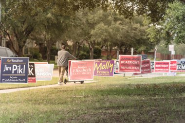 IRVING, TX, USA-OCT 22, 2018:Rear view double stroller near row of yard sign at residential street for primary election day in Dallas county, Texas. Signs greeting early voters, political party poster clipart