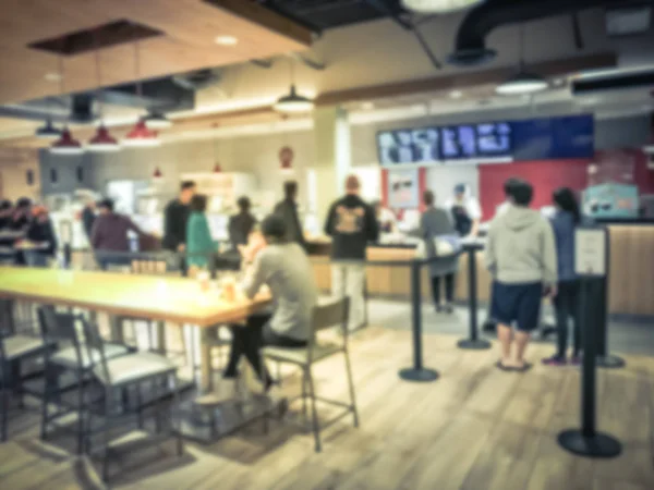 Vintage tone blurred diverse group of customers waiting in line to checkout at bakery shop in Texas, America. Large wall mount led menu board digital signage. Abstract background diverse crowd wait