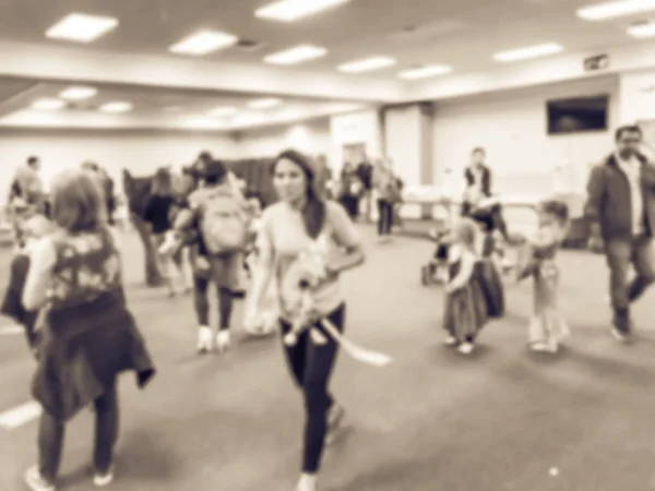 Vintage tone blurred abstract kids and parents enjoy indoor Halloween party at school in Texas, America. Defocused children with costumes at fall fun games, shape links