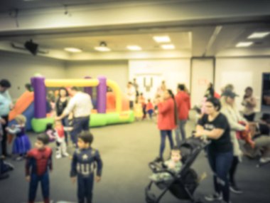 Soyut bulanık çeşitli çok ırklı çocuklar oyun atlama şişme sıçrama ev zevk. Ebeveynler ve çocuklar ile gezinmek kapalı okulda Cadılar Bayramı partisi Texas, Amerika defocused