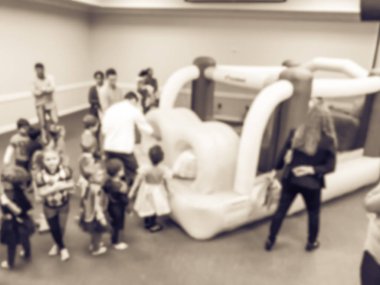 Vintage sesi soyut bulanık çeşitli çok ırklı çocuklar oyun atlama şişme sıçrama ev zevk. Ebeveynler ve çocuklar kapalı okulda Cadılar Bayramı partisi Texas, Amerika defocused