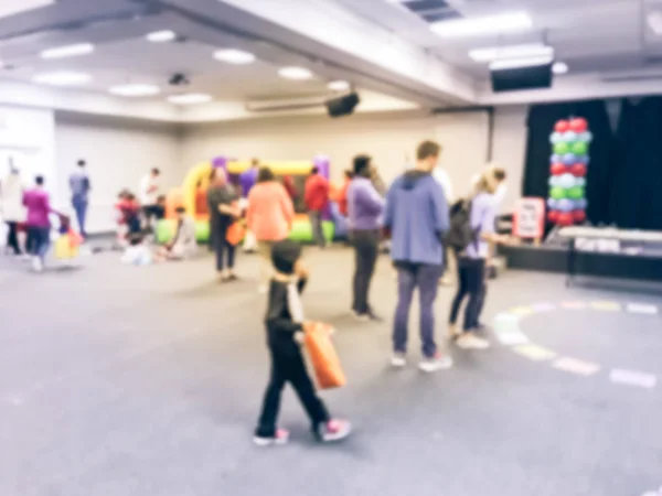 Blurred motion diverse multiethnic children enjoy circle game in Texas, America. Defocused parents and kids at school indoor Halloween party.