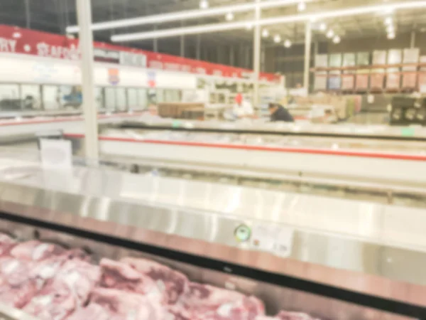 Blurred abstract meat department at wholesale store in America. Defocused customer shopping for fresh raw beef, chicken, seafood from huge open fridge, cooler.