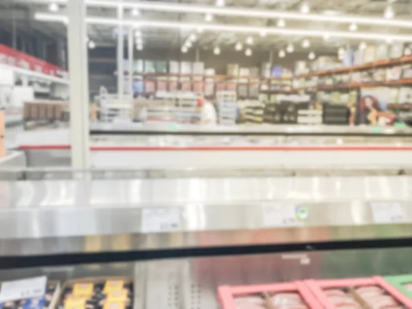 Blurred abstract meat department at wholesale store in America. Defocused customer shopping for fresh raw beef, chicken, seafood from huge open fridge, cooler.