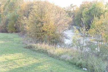 Güzel nehir kenarında park ile düşmek yeşillik canlı renk ve güneş ağaçların Carrollton, Texas, ABD ile bakmak. Sarı sonbahar çarpıcı günbatımında bırakır