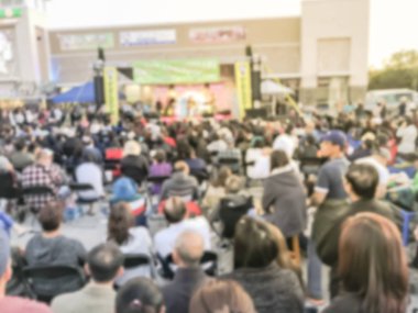 Bulanık soyut kalabalık insan ayakta açık hava aşamada katlanabilir kamp sandalyede oturuyor. Ufuk sayıda izleyici açık hava Müzik Festivali'nde günbatımında kendilerini zevk