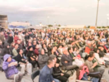 Bulanık soyut kalabalık insan ayakta açık hava aşamada katlanabilir kamp sandalyede oturuyor. Ufuk sayıda izleyici açık hava Müzik Festivali'nde günbatımında kendilerini zevk