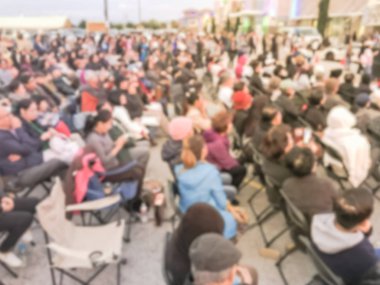 Bulanık soyut kalabalık insan ayakta açık hava aşamada katlanabilir kamp sandalyede oturuyor. Ufuk sayıda izleyici açık hava Müzik Festivali'nde günbatımında kendilerini zevk