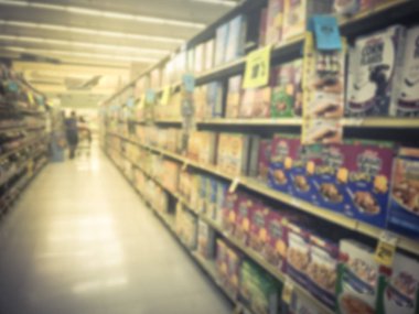 Motion blurry customer shopping for variety of convenient breakfast, juices, sport drinks, snack bars, cereal at grocery store in Texas, USA. Defocused background of aisle shelves foods at supermarket clipart