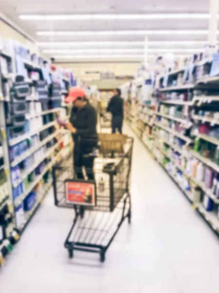 Blurred motion customer with cart shopping for personal care with price tags as hair accessories, shampoo, hair care, cosmetics, bar soap, feminine care at grocery store in Texas, USA