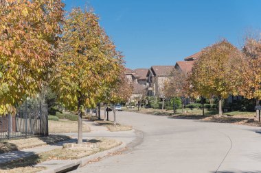 Yeni geliştirme alt bölümü ile Dallas, Texas banliyösü sakin yerleşim sokakta sonbahar güneşli. Sarı düşen yapraklar kaldırım mahalle. Amerika'da sokakta park edilmiş araba