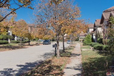 Yeni geliştirme alt bölümü ile Dallas, Texas banliyösü sakin yerleşim sokakta sonbahar güneşli. Sarı düşen yapraklar kaldırım mahalle. Amerika'da sokakta park edilmiş araba