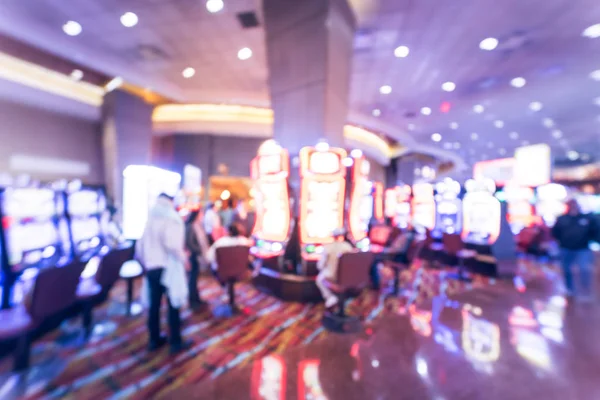 Typical gambling abstract background. Blurred slot machines, themed game, roulette slot poker 777, armed bandit with players at casino in Oklahoma. Colorful illuminated light on row of digital machine