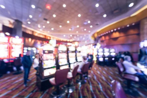 Typical gambling abstract background. Blurred slot machines, themed game, roulette slot poker 777, armed bandit with players at casino in Oklahoma. Colorful illuminated light on row of digital machine