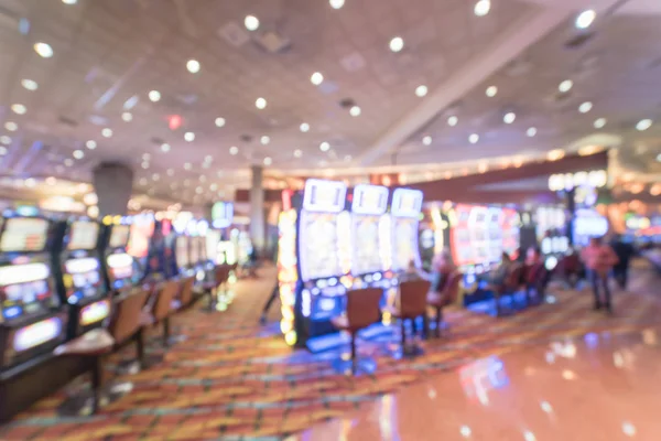 Typical gambling abstract background. Blurred slot machines, themed game, roulette slot poker 777, armed bandit with players at casino in Oklahoma. Colorful illuminated light on row of digital machine