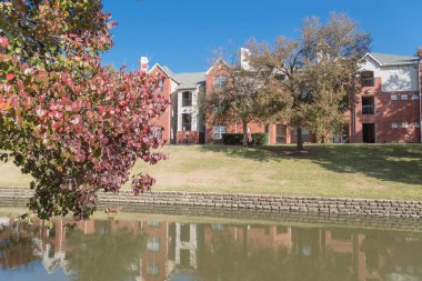 Renkli sonbahar yaprakları ağaçların Irving, Texas, ABD tarafından çevrili tipik multistorey nehir kenarında daire konut kompleksi güzel ayna yansıması.