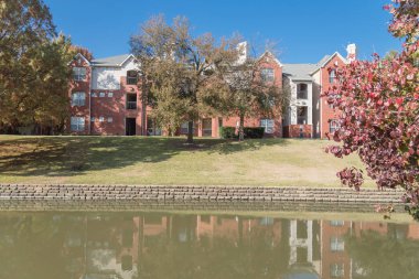 Renkli sonbahar yaprakları ağaçların Irving, Texas, ABD tarafından çevrili tipik multistorey nehir kenarında daire konut kompleksi güzel ayna yansıması.