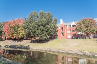 Renkli sonbahar yaprakları ağaçların Irving, Texas, ABD tarafından çevrili tipik multistorey nehir kenarında daire konut kompleksi güzel ayna yansıması.