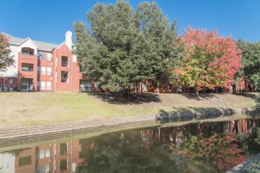 Renkli sonbahar yaprakları ağaçların Irving, Texas, ABD tarafından çevrili tipik multistorey nehir kenarında daire konut kompleksi güzel ayna yansıması.