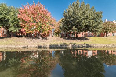 Renkli sonbahar yaprakları ağaçların Irving, Texas, ABD tarafından çevrili tipik multistorey nehir kenarında daire konut kompleksi güzel ayna yansıması.
