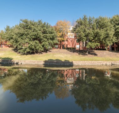 Renkli sonbahar yaprakları ağaçların Irving, Texas, ABD tarafından çevrili tipik multistorey nehir kenarında daire konut kompleksi güzel ayna yansıması.