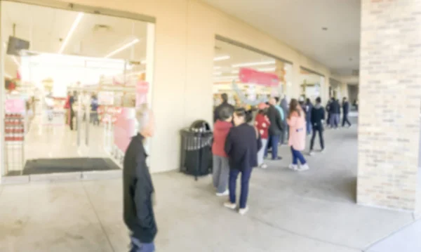 Panorama view long line of people waiting at the entrance of grocery store in Carrollton, Texas, USA. Defocused background shoppers on Black Friday shopping deals