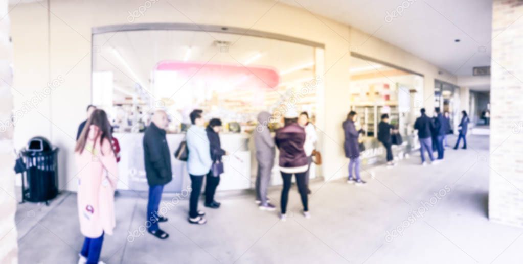 Panorama view long line of people waiting at the entrance of grocery store in Carrollton, Texas, USA. Defocused background shoppers on Black Friday shopping deals