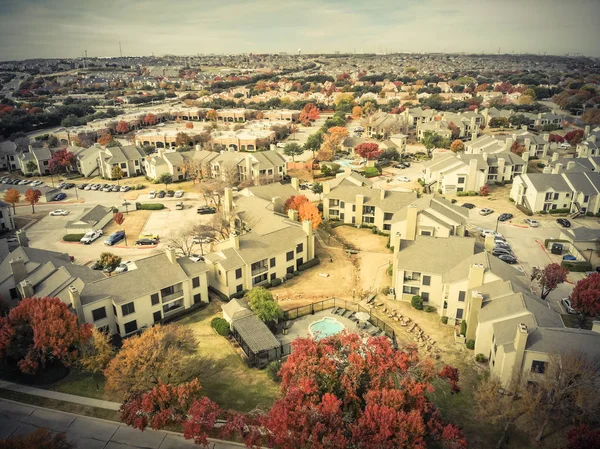 Vintage tone aerial view apartment building complex with colorful fall foliage leaves near suburban Dallas, Texas, USA. Flyover beautiful autumn scene in rental housing subdivided unit flats