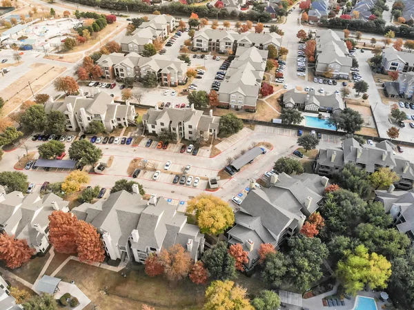 Aerial view apartment building complex with colorful fall foliage leaves near suburban Dallas, Texas, USA. Flyover beautiful autumn scene in rental housing subdivided unit flats