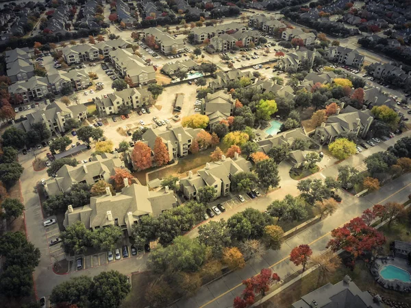 Vintage tone aerial view apartment building complex with colorful fall foliage leaves near suburban Dallas, Texas, USA. Flyover beautiful autumn scene in rental housing subdivided unit flats