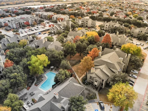 Aerial view apartment building complex near riverside residential neighborhood. Colorful fall foliage leaves suburban Dallas, Texas, USA. Flyover autumn scene in rental housing subdivided unit flats