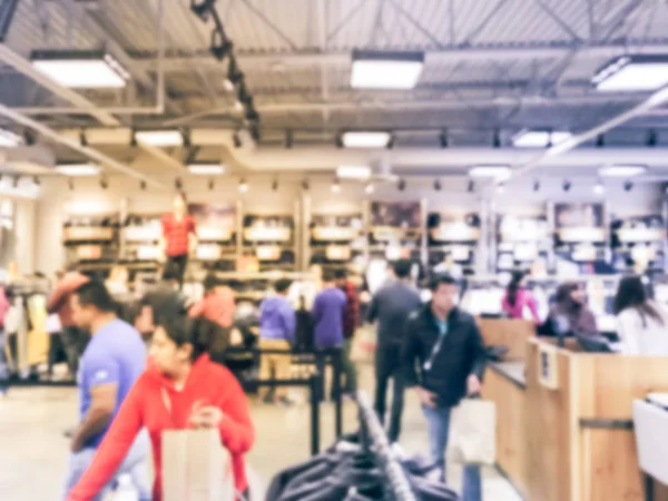 Blurred motion long line of diverse customers waiting to checkout at apparel, accessories store in Texas, USA. Defocused abstract crowed people retractable stanchions queue barrier, holiday shopping