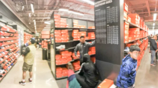 Blurry background customers browsing for shoes at giant outlet s — Stock Photo, Image