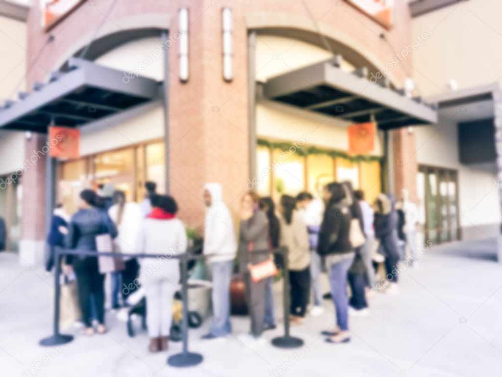 Blurred abstract long line of customer waiting at entrance for fashion store open during Black Friday in outlet mall, Texas, USA. Defocused holiday shopping background, retractable belt stanchion