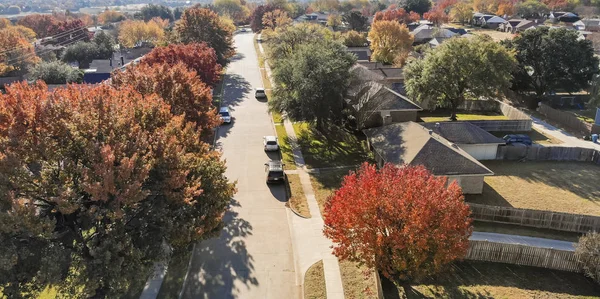 Panorama top view beautiful neighborhood in Coppell, Texas, USA in autumn season. Row of single-family home with attached garage, garden, surrounded by colorful fall foliage leaves under blue sky