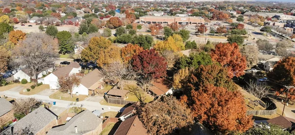 Panorama top view beautiful neighborhood in Coppell, Texas, USA in autumn season. Row of single-family home with attached garage, garden, surrounded by colorful fall foliage leaves under blue sky