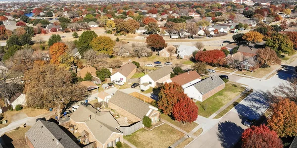 Panorama top view beautiful neighborhood in Coppell, Texas, USA in autumn season. Row of single-family home with attached garage, garden, surrounded by colorful fall foliage leaves under blue sky